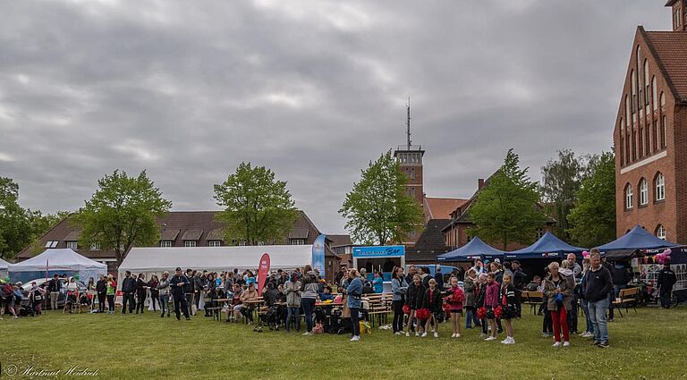 Eine Menschenmenge in einer Festkulisse auf einer Wiese, mit Zelten im Hintergrund