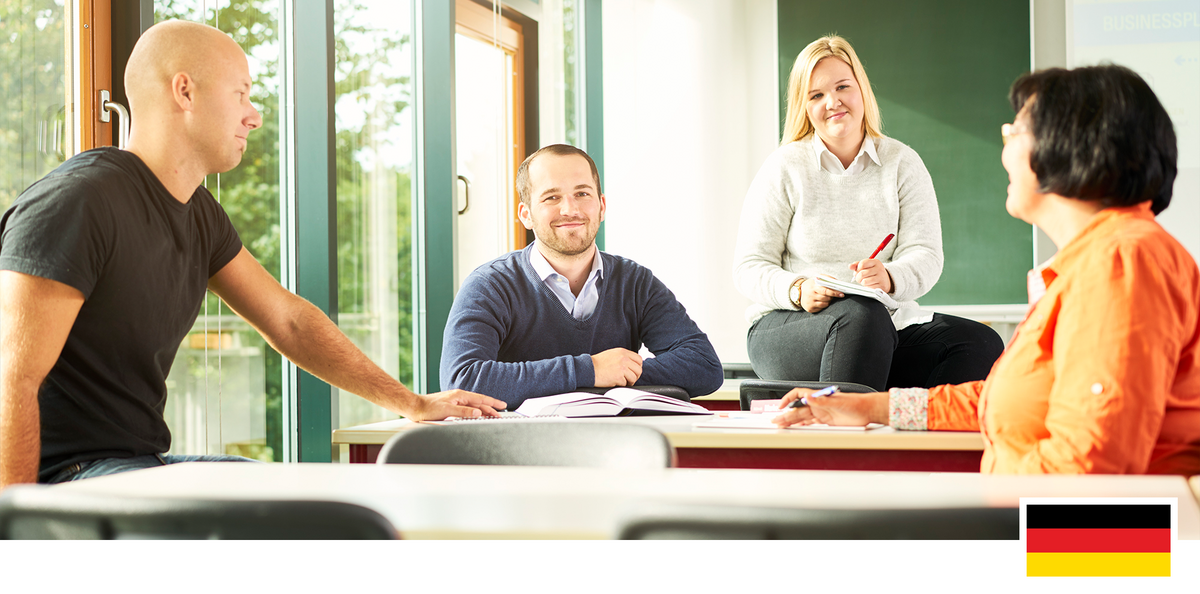 Headerfoto: Studierende und eine Professorin in einem Hörsaal im Gespräch und Austausch