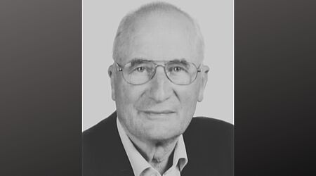 Ein Schwar-weiß-Bild auf dunklem Grund von einem Mann im gehobenen Alter.