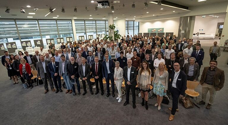 Eine Gruppe von Menschen steht in einem Raum für das Gruppenbild