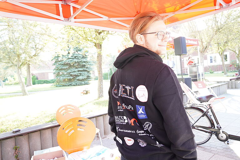 Ein junger mann im Schwarzen Hoodie mit vielen Logos darauf.