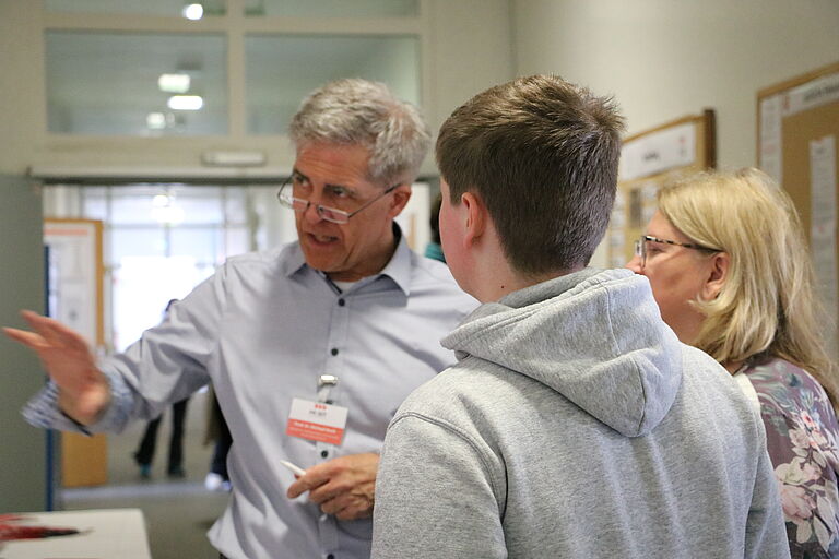 ein Mann, Prof. Dr. Koch, im Gespräch mit einer Frau und einem jungen Mann