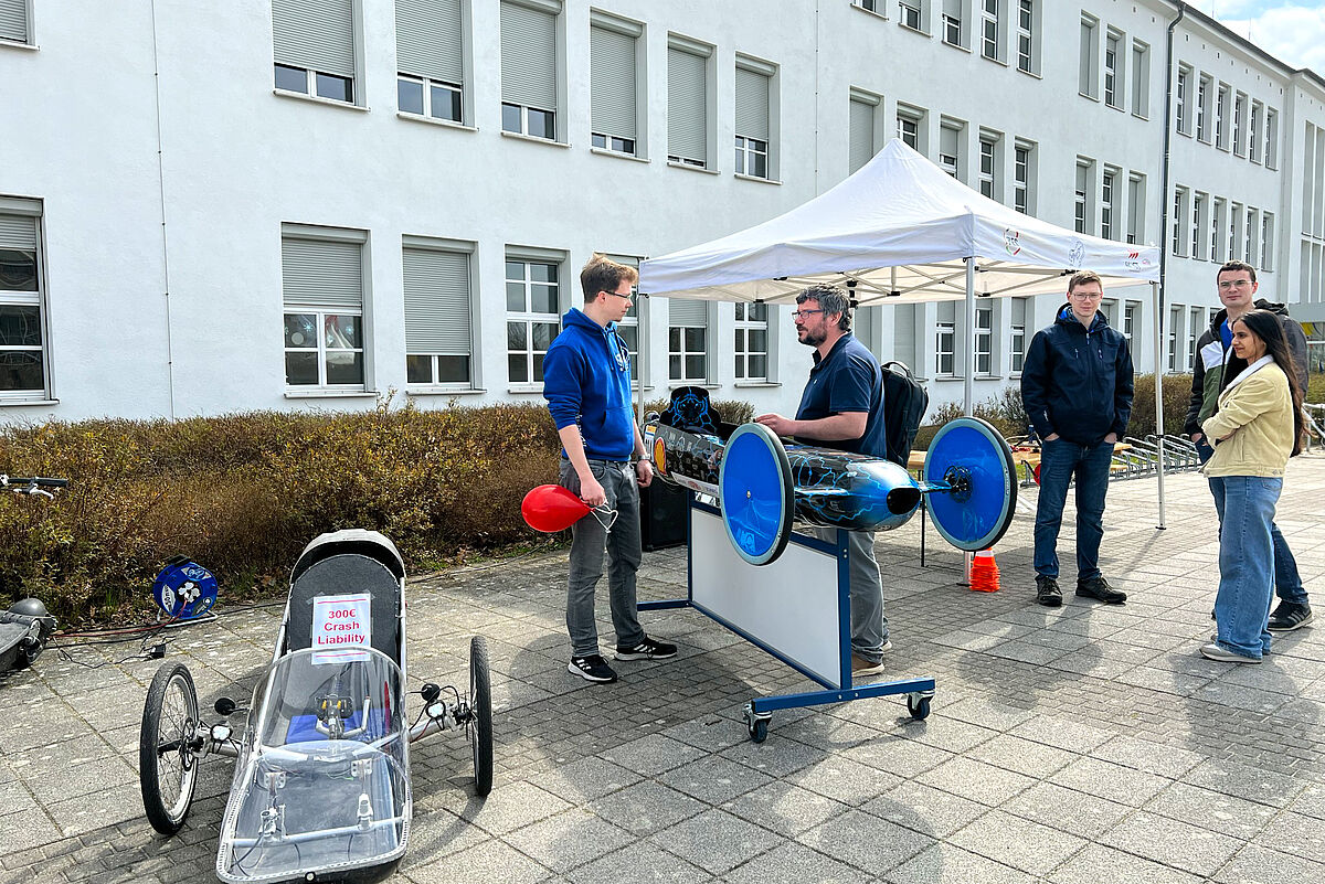 Studierende des TheiGer Teams mit Ihren Fahrzeugen im Gespräch.