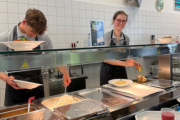 2 Studierende stehen hinter dem Mensa-Tresen