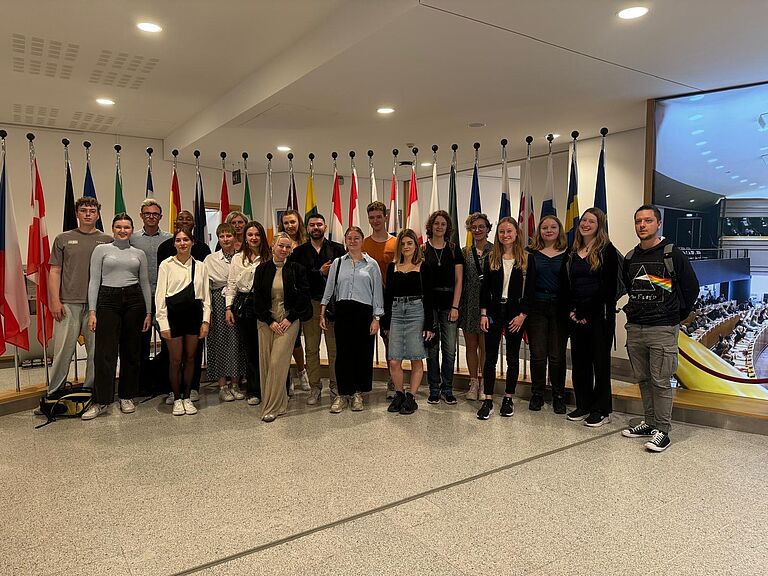 Gruppenbild vornehmlich junger Menschen in einem offiziell wirkenden Saal mit glänzendem Marmorboden