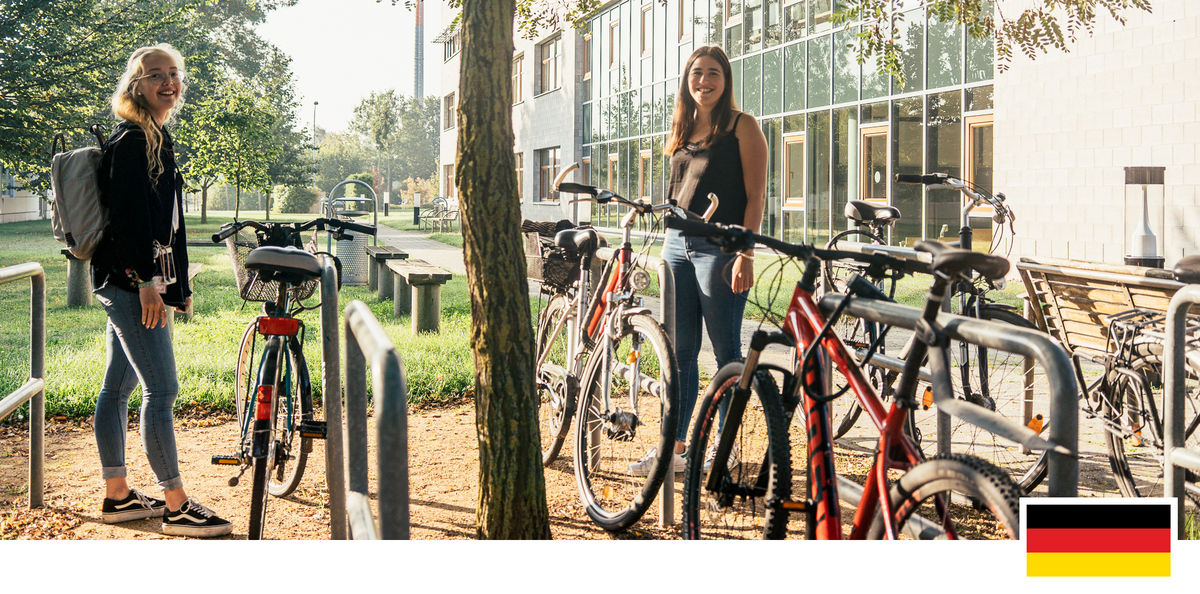 Headerfoto: Zwei Studierende stehen vor der Fakultät für Wirtschaft vor ihren Fahrrädern
