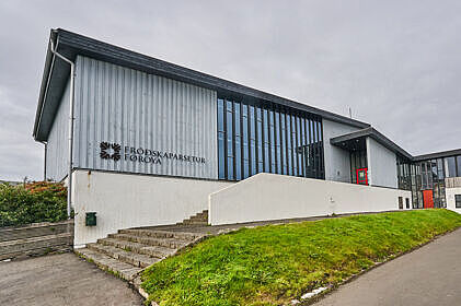 Aufnahme eines grau-blauen gebäudes mit gläsernem EIngangsbereich der University of the Faroe Islands