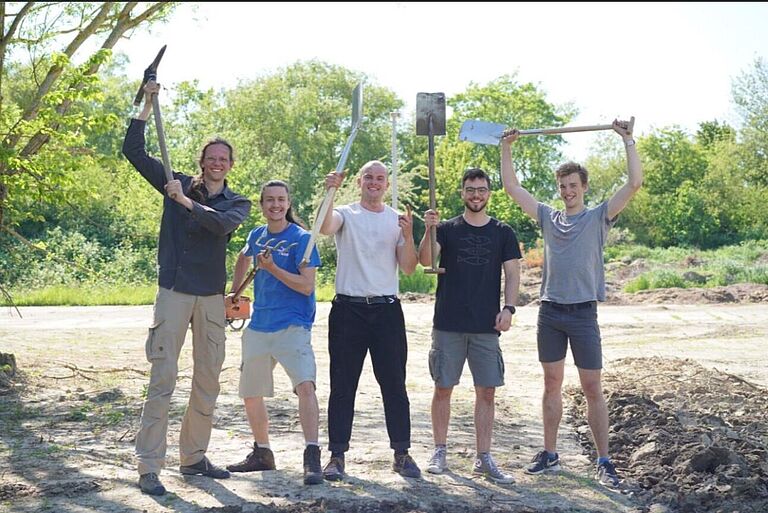 eine gruppe junger Männer reißt die Spaten hoch