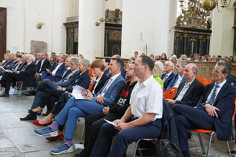 Mehrere Menschen sitzen in Reihe in einer Kirche