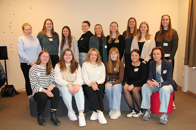 eine Gruppe Studentinnen sitzt zusammen mit ihrer Coachin für ein Gruppenfoto