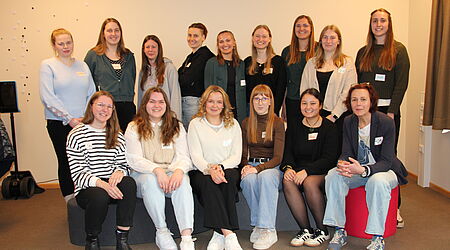 eine Gruppe Studentinnen sitzt zusammen mit ihrer Coachin für ein Gruppenfoto