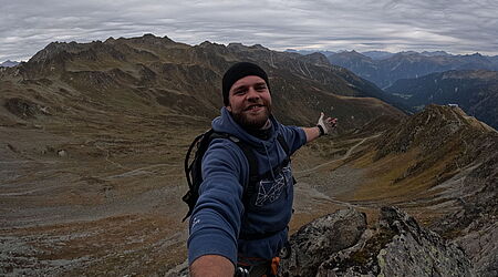 ein Mann auf dem Gipfel eines Berges, das Bild selbst aufnehmend