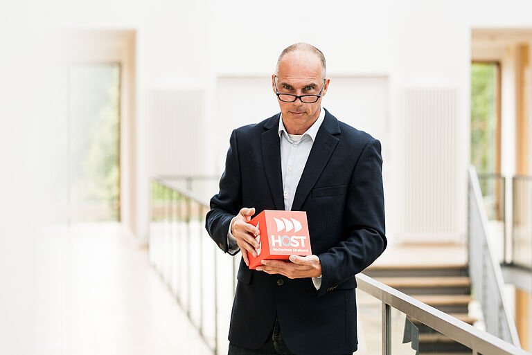 Prof. Dr. sc. hum. Dipl.-Ing. Holger Specht steht in der Mitte mit Würfel in der Hand