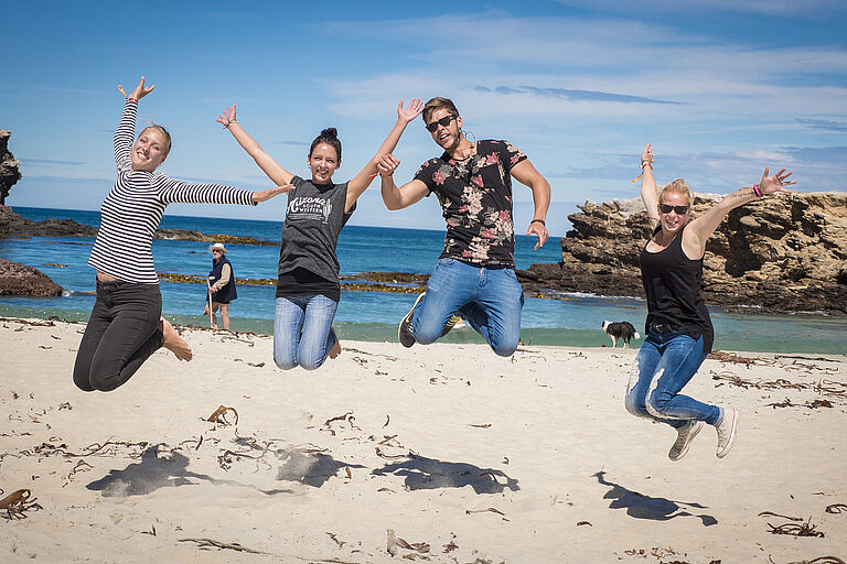 Springende Studenten am Strand