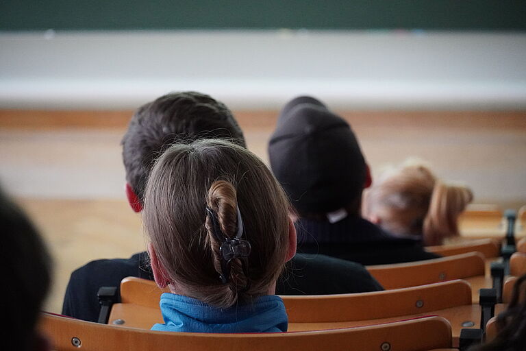 Die Hinterköpfe von jungen Menschen in einem Hörsaal